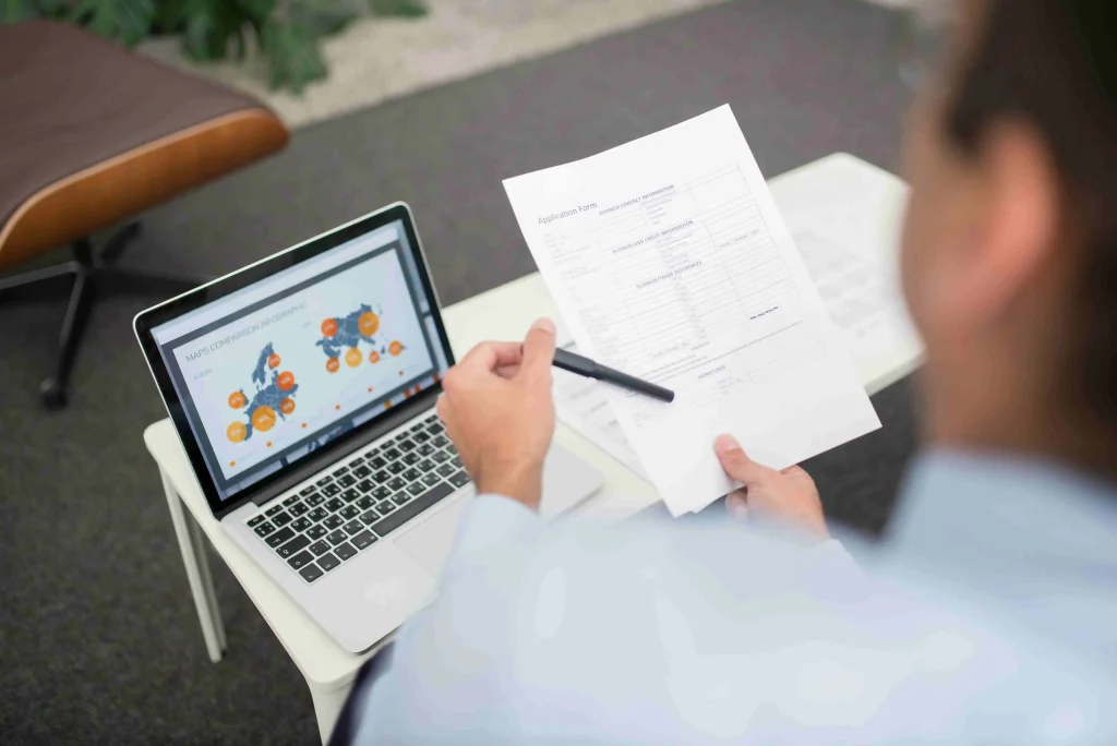 Een moderne administratief medewerker gemeente analyseert complexe data en burgergegevens op een laptop in een kantooromgeving.