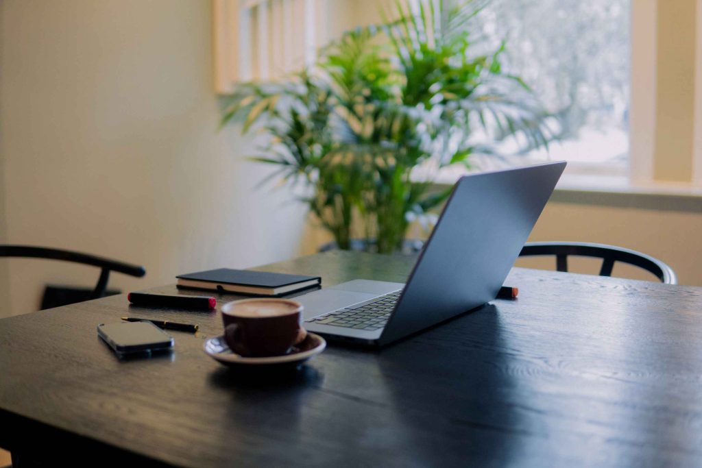 DAFT visum Nederland: een digitale nomade werkt op een laptop met uitzicht op een typisch Amsterdamse gracht.
